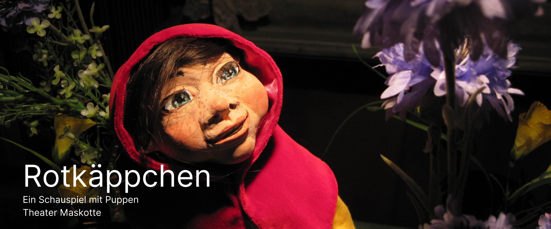 Rotkäppchen als Puppe schaut auf eine Blume